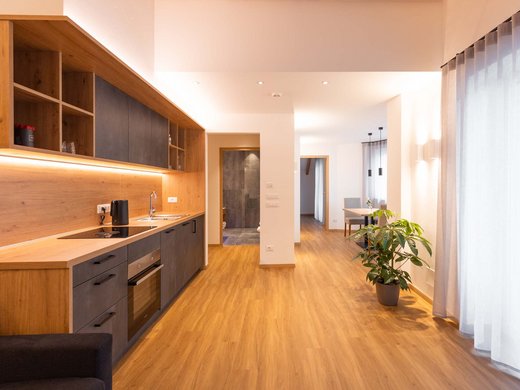 Ferienwohnung im Eisacktal: Am Brunnen Apartments Moderner Flur mit Holzboden, Küchenzeile und großem Fenster mit Vorhängen