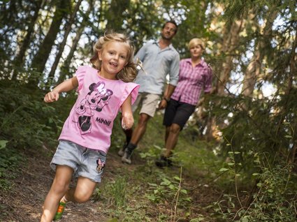 Appartamento a Naz-Sciaves Bambina che corre felice nel bosco, genitori la seguono sullo sfondo